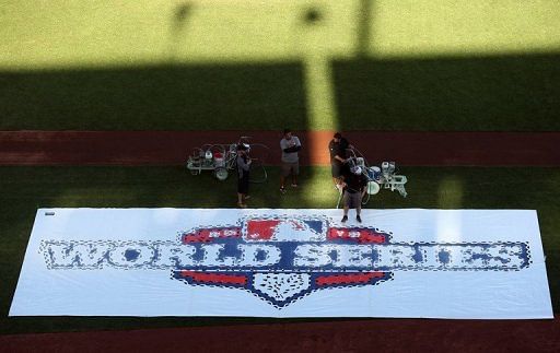 Grounds crew paint the World Series logo on the grass outside the first base line