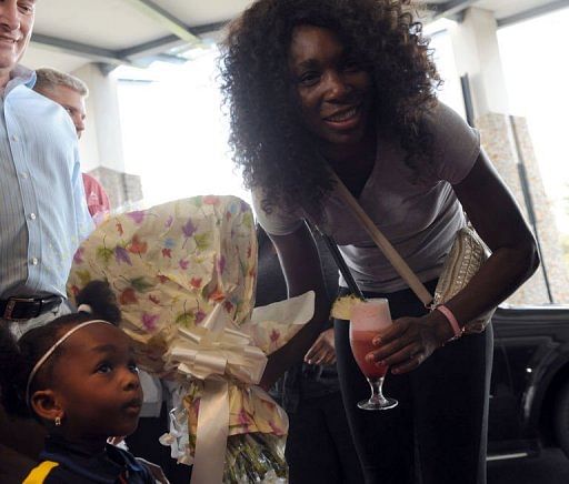 A girl gives flowers to US tennis star Venus Williams on her arrival at the Federal Palace hotel in Lagos, Nigeria