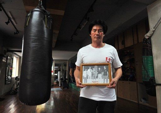 South Korean trainer Kim Yoon-Gu, 56, holds a picture showing boxer Kim Duk-Koo, taken in 1981