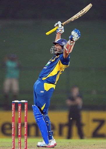 Sri Lankan cricketer Tillakaratne Dilshan raises his bat and helmet in celebration after scoring a century