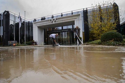 Cleaners work outside the flooded International Olympic Committee headquarters in Lausanne