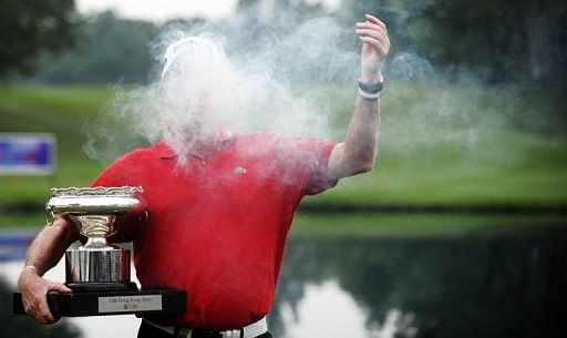 Miguel Angel Jimenez of Spain jokes with his cigar while posing with the trophy