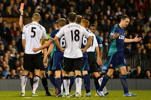 Fulham&#039;s Brede Hangeland (L) receives a straight red card from referee Lee Probert