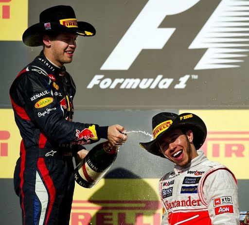Sebastian Vettel (L) sprays champagne on Lewis Hamilton