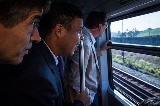 Ronaldo (C) and FIFA Secretary General Jerome Valcke (R) ride a train to the construction site of the Itaquerao stadium