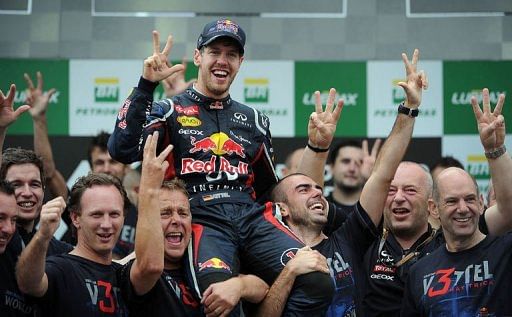 German Formula One driver Sebastian Vettel (C) celebrates his F-1 World Championship with members of the Red Bull team