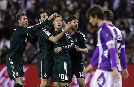 Real Madrid&#039;s midfielder Mesut Ozil (C) celebrates with teammates Sergio Ramos (L) and Xabi Alonso (R)
