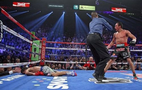 Referee Kenny Bayless (C) holds back Juan Manuel Marquez (R) as Manny Pacquiao (L) lies face down on the mat