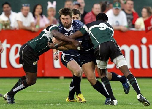David Tait (C) fends off several Zimbabwe players at the IRB World Sevens Series in Dubai on December 4, 2009