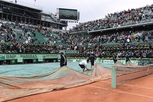 Staff remove the covers from Centre Court at Roland Garros on June 8, 2012