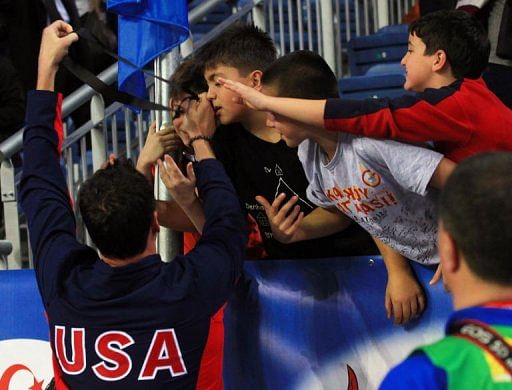 Ryan Lochte (L) of USA gives his medal to a Turkish child, Arda Cakmak (2ndL)