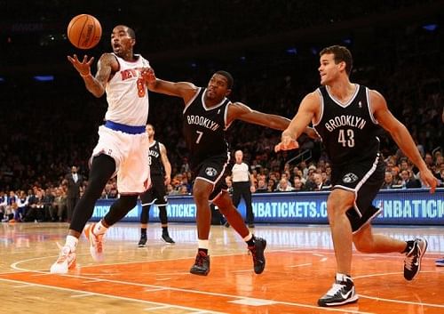 The Knicks' J.R. Smith (L) grabs a rebound as the Nets' Joe Johnson (C) defends during their game on December 19, 2012