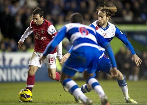 Arsenal&#039;s Santi Cazorla (L) fights for the ball with Reading&#039;s Kaspars Gorkss (R), in Reading, on December 17, 2012