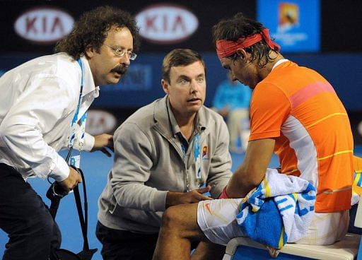 Courtside trainers attend to Rafael Nadal&#039;s knee injury during the Australian Open, in Melbourne, on January 26, 2010