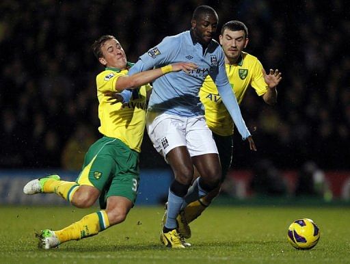 Norwich City&#039;s defender Steven Whittaker falls to the ground as he challenges Manchester City&#039;s midfielder Yaya Toure