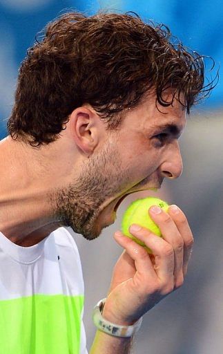 Grigor Dimitrov of Bulgaria bites a ball during his semi-final match against Marcos Baghdatis on January 5, 2013