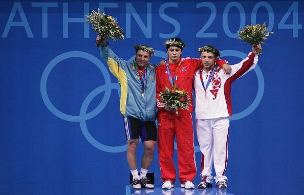 ATHENS - AUGUST 19:  (L-R) Silver medal winner Sergey Filimonov, gold medal winner Taner Sagir and bronze medal winner Oleg Perepetchenov pose on the podium during the medal ceremony of the men&#039;s 77 kg category weightlifting competition on August 19, 2004 during the Athens 2004 Summer Olympic Games at Nikaia Olympic Weightlifting Hall in Athens, Greece. 