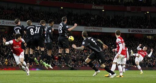 Arsenal&#039;s Lukas Podolski (R) takes a free kick at the Liverpool goal in London on January 30, 2013