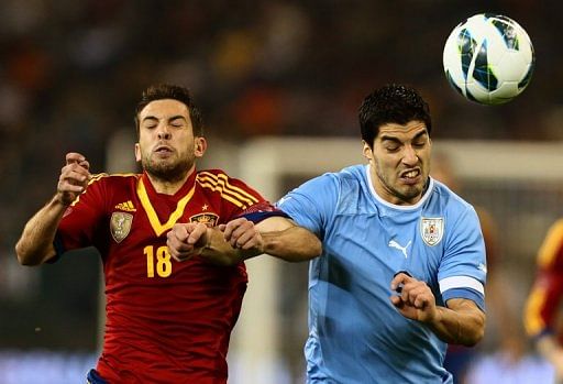 Uruguay&#039;s Luis Suarez (R) holds off Spain&#039;s Jordi Alba during the friendly in Doha on February 6, 2013
