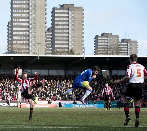 Chelsea&#039;s Juan Mata (C) attempts to block a shot from Brentford&#039;s Adam Forshaw (L), at Griffin Park, on January 27, 2013