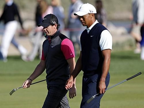 Tiger Woods of the US (R) walks with Northern Ireland's Rory McIlroy at the Abu Dhabi Golf Club on January 17, 2013