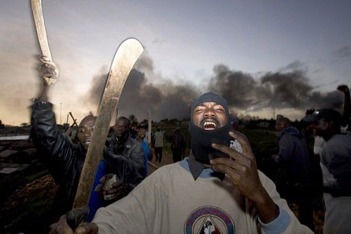 Men wave machetes during demonstrations on December 30, 2007 at a slum in Nairobi