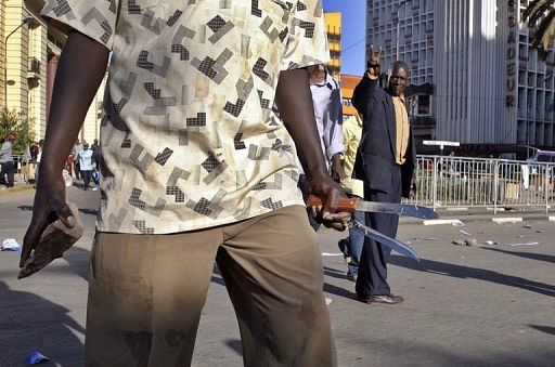 A supporter of Kenya&#039;s Party of National Unity wields a stone and knives during clashes on December 24, 2007 in Nairobi