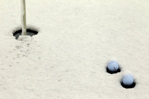 Golf balls lie in the snow on the practice putting green as play was suspended, on February 20, 2013