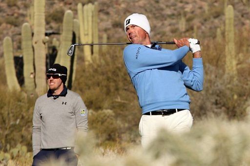 Matt Kuchar hits a tee shot on the 16th hole as Hunter Mahan looks on February 24, 2013 in Arizona