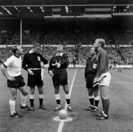 Referee Gottfried Dienst, of Switzerland, tosses the coin before the start of the World Cup final at Wembley between England and West Germany. He is watched by German captain Uwe Seeler, (left), the Russian linesman Tofik Bakhramov (looking at watch) and English captain Bobby Moore (1941 - 1993) (right).