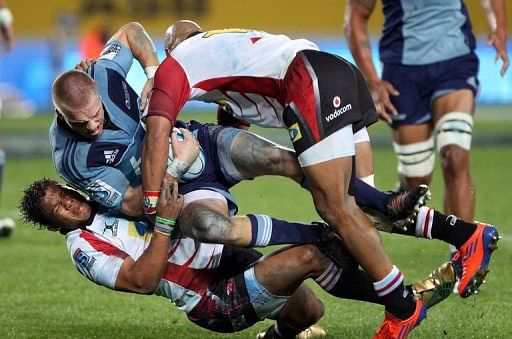 Blues&#039; Gareth Anscombe is tackled by Lions&#039; Elton Jantjies (L) and Lionel Mapoe (R), in Auckland, on May 11, 2012