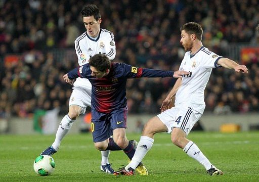 Barcelona&#039;s Lionel Messi tries to find a way through Real Madrid&#039;s Jose Callejon (L) and  Xabi Alonso February 26, 2013