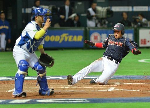 Japan&#039;s Seiichi Uchikawa (R) arrives at the home plate in Fukuoka on March 2, 2013