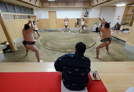 Stablemaster Tadahiro Otake (seated) watches as his sumo wrestlers train at a sumo stable in Tokyo on February 14, 2013