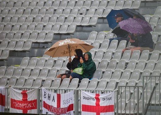 Fans take cover as poor light and rain prevented play on the first day of the opening Test on March 6, 2013
