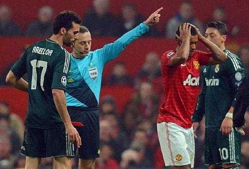 United midfielder Nani (R) holds his head as referee Cuneyt Cakir sends him off at Old Trafford on March 5, 2013