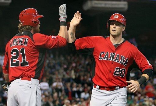 Michael Saunders (R) of Canada high-fives Adam Loewen after scoring a first-inning run against Mexico on March 9, 2013