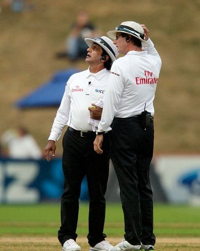 Umpires Asad Rauf (L) and RJ Tucker gauge the weather in Wellington on March 17, 2013