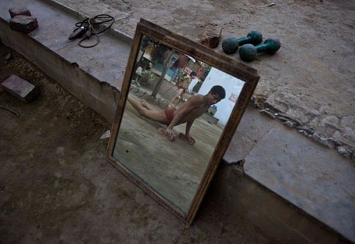 A budding Indian wrestler does push-ups  at a traditional mud akhara in New Delhi on March 6, 2013