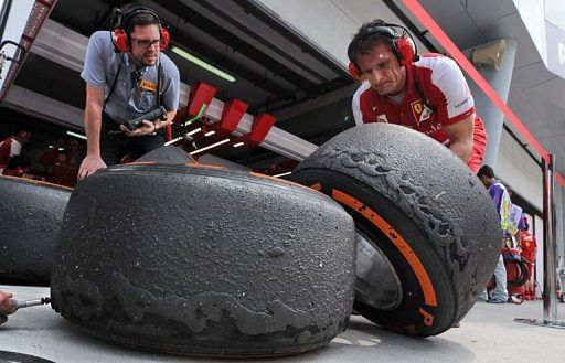 Ferrari crew look at wear on tyres in Sepang on March 22, 2013 during practice for the Malaysian Grand Prix