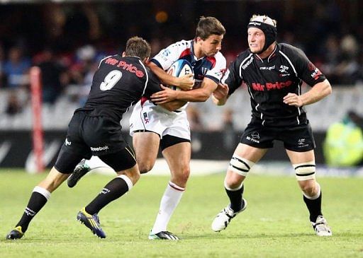 Nick Phipps of the Rebels (C) is tackled by Cobus Reinach (L) and Franco van der Merwe (R) of the Sharks, March 23, 2013