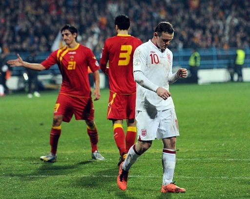 England forward Wayne Rooney (R) trudges off after the draw at Montenegro on March 26, 2013