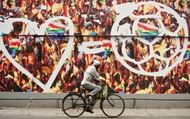 An Indian man cycles past an advertiseme