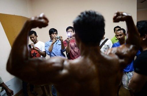 A bodybuilder flexes his muscles for fans backstage at the SEA Games selection contest in Yangon on February 12, 2013
