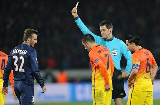 German referee Wolfgang Stark (C) hands a yellow card to Paris Saint-Germain&#039;s David Beckham in Paris on April 2, 2013