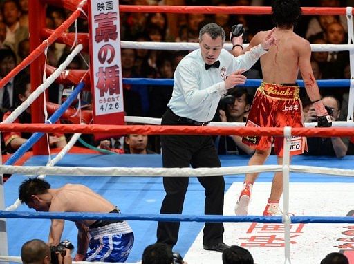 A referee separates Shinsuke Yamanaka of Japan (R) and Malcolm Tunacao of the Philippines (L) in Tokyo on April 8, 2013