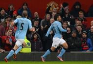 City's Sergio Aguero (R) celebrates in front of the United fans after scoring at Old Trafford on April 8, 2013