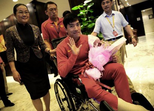 Chinese hurdler Liu Xiang waves as he arrives back in Shanghai on August 14, 2012