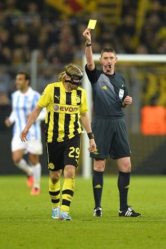 Craig Thomson issues a yellow card to Dortmund&#039;s Marcel Schmelzer at the match against Malaga on April 9, 2013