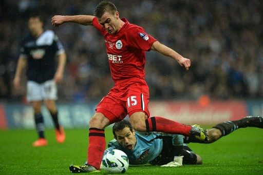 Wigan Athletic&#039;s Callum McManaman shoots to score as Millwall&#039;s goalkeeper David Forde (down) looks on, April 13, 2013